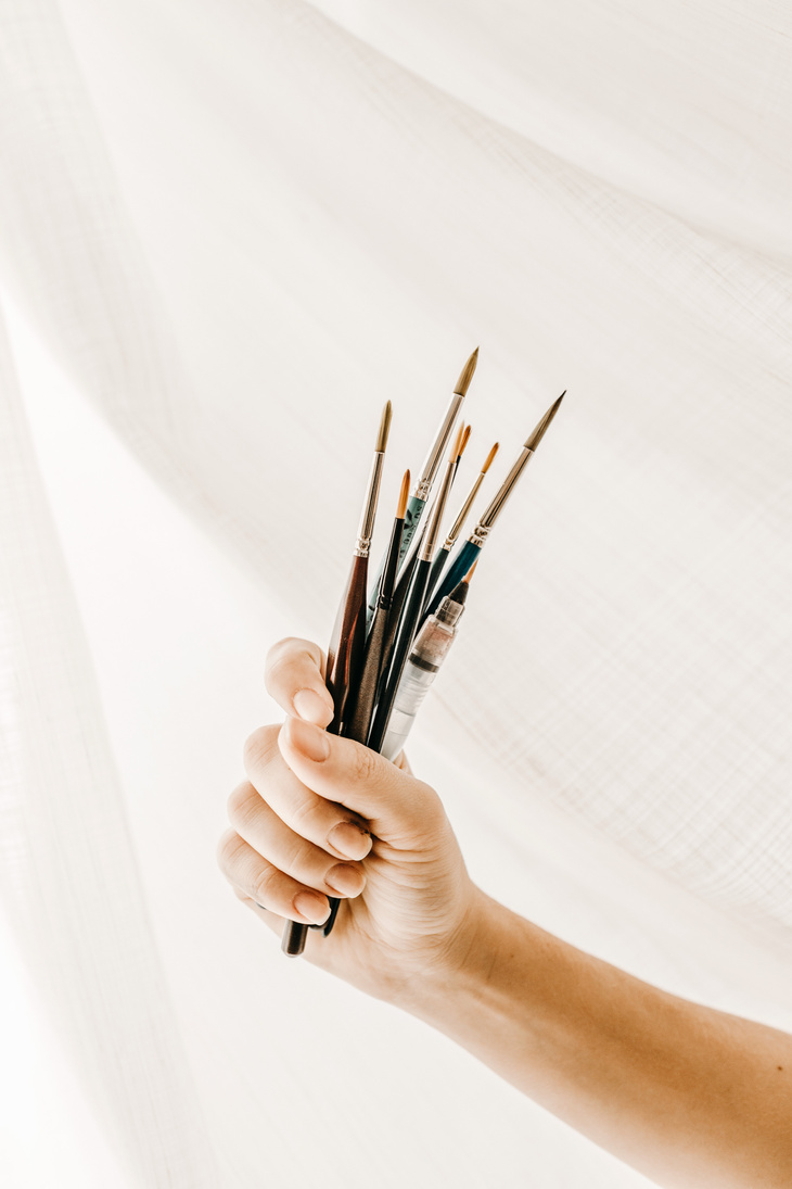 Crop artist with brushes against cloth